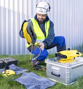 Person bereitet eine gelbe Unterwasserdrohne für die Inspektion eines Löschwasserbehälters bzw. Sprinklertanks vor.