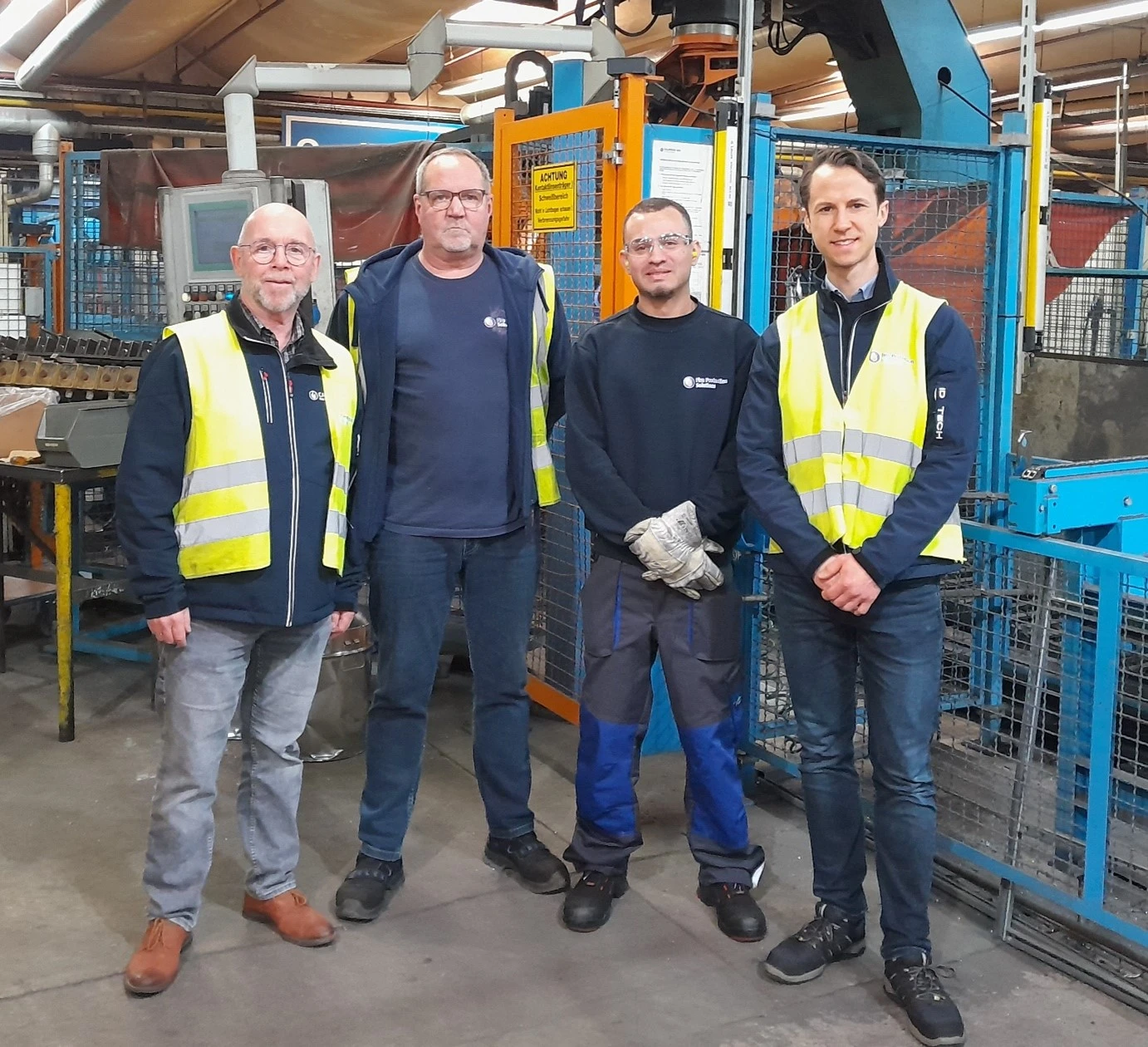 Vier Mitarbeitende in Warnwesten und Arbeitskleidung stehen in einer Fertigungshalle von Calanbau-GFA Feuerschutz in Sarstedt