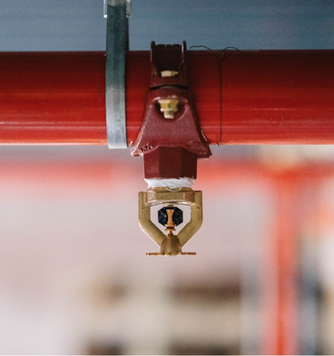 Nahaufnahme eines Sprinklers an einer roten Rohrleitung zur Brandbekämpfung im Rahmen eines Brandschutzversuchs